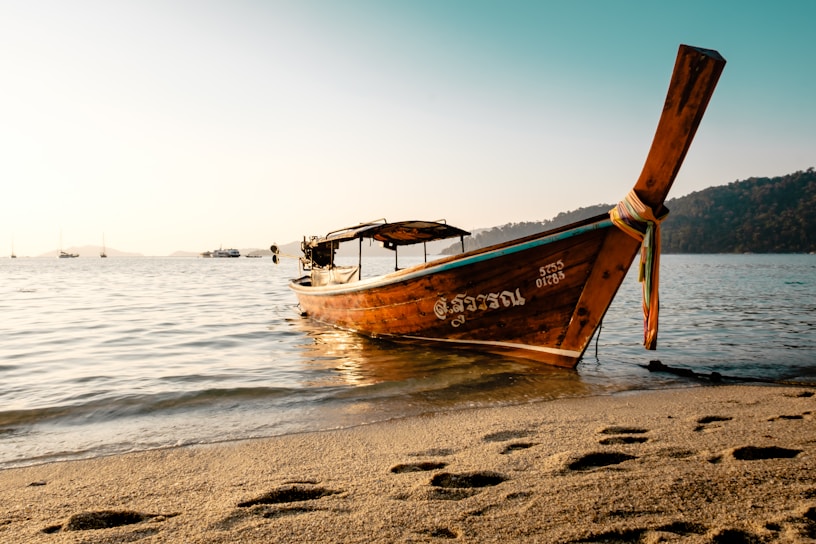 A vibrant sunset over Patong Beach with colorful longtail boats resting on the shore.