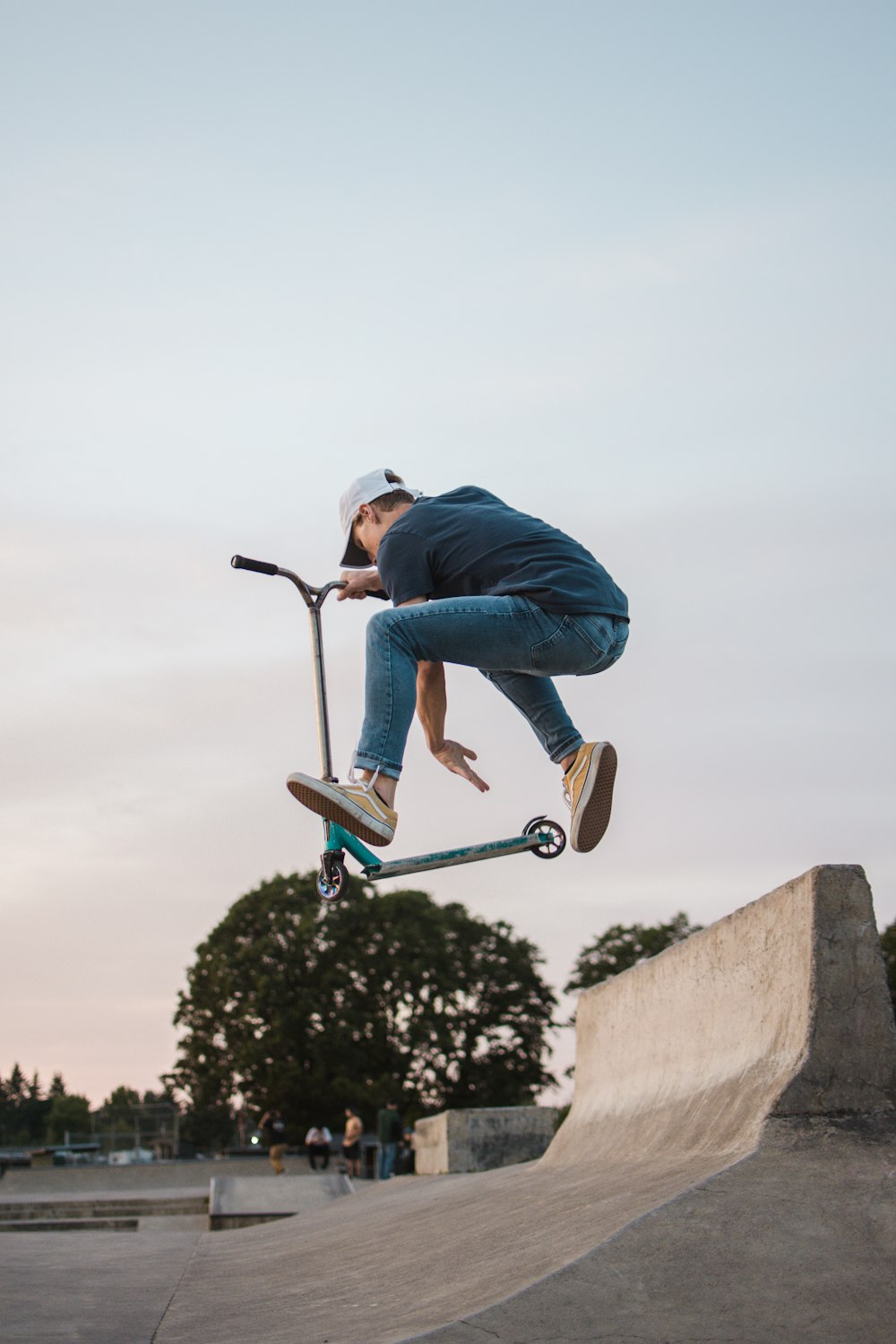 man in hoodie jumping with kick scooter