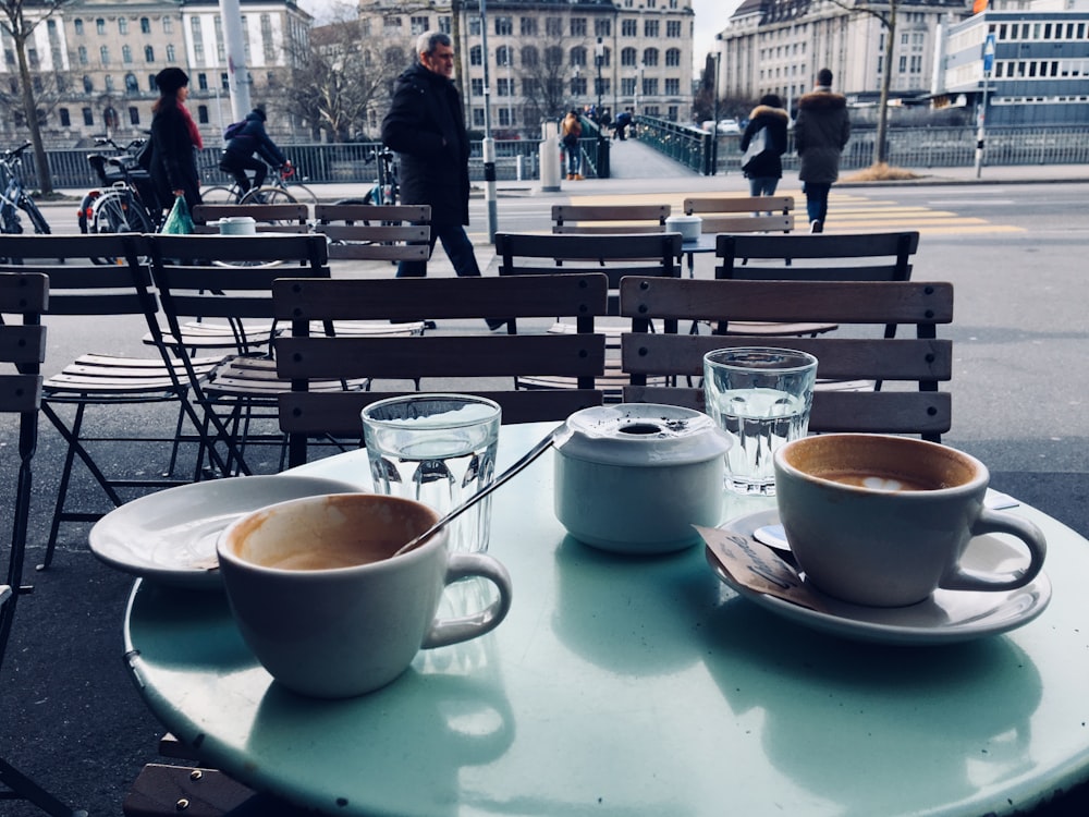 two white ceramic teacups on round teal table