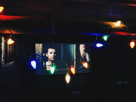 flat screen television near string lights