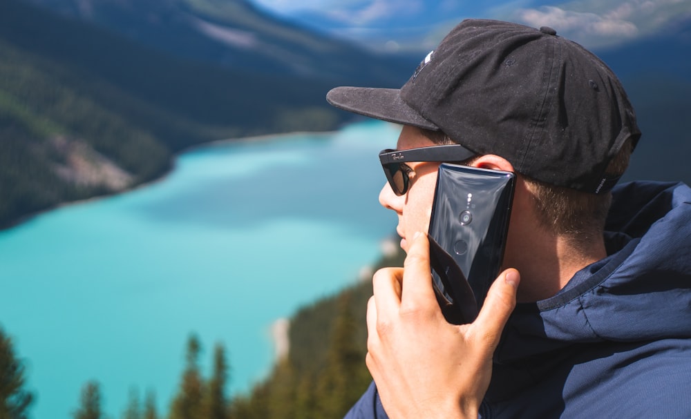 man near outdoor holding smartphone while starring on lake during daytime