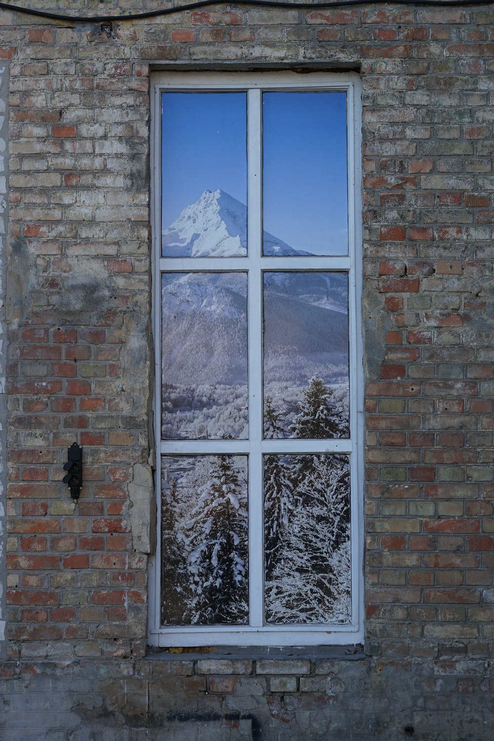 Fensterscheibe, in der sich Berge und Bäume spiegeln