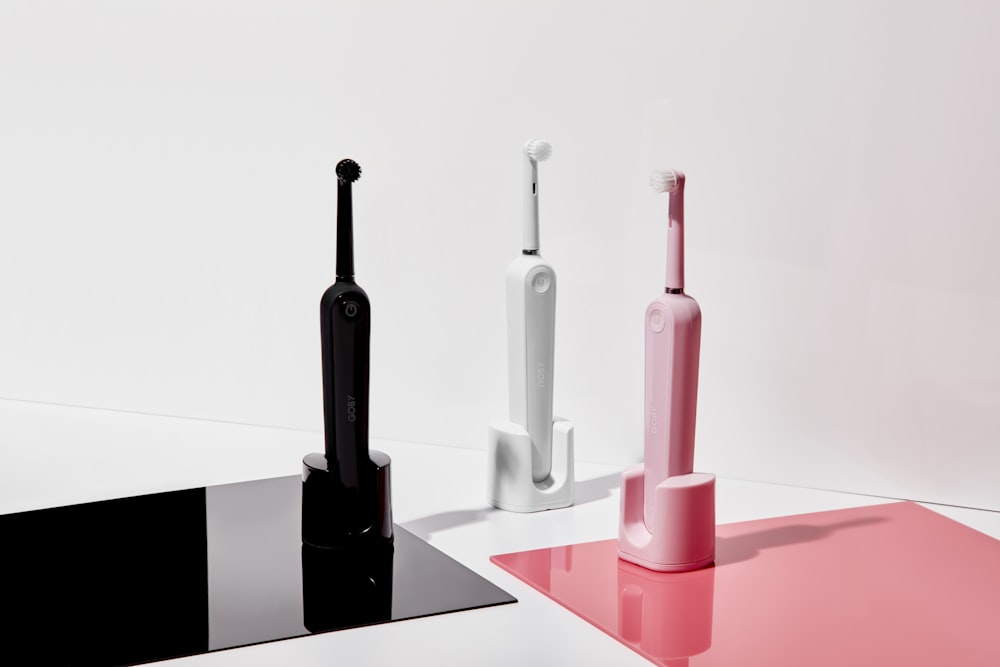 three assorted-color electric toothbrushes