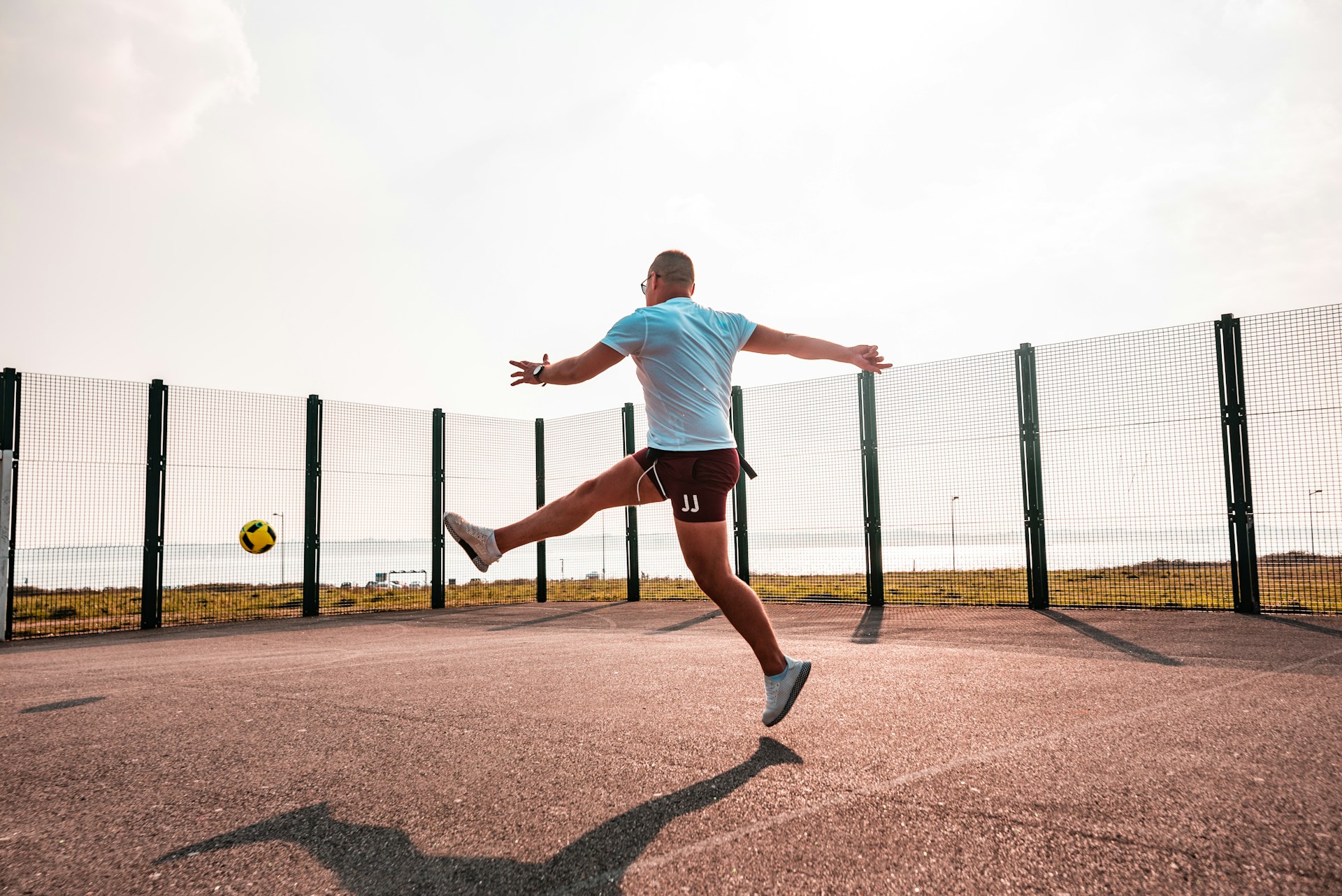 A dynamic soccer player mid-kick on a vibrant green field under a clear blue sky.