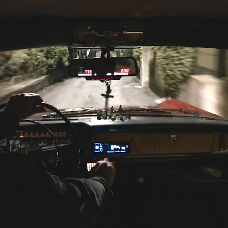 A friendly driving instructor giving directions inside a car, with Canterbury streets visible outside.