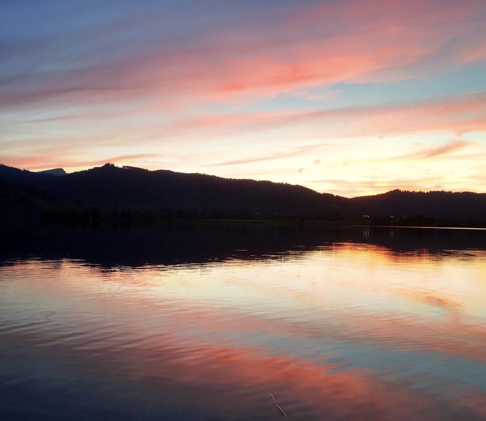 body of water across mountains photo during dusk