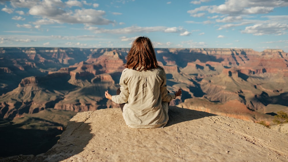 woman sitting on a hill overlooking the Grand Canyon and meditating