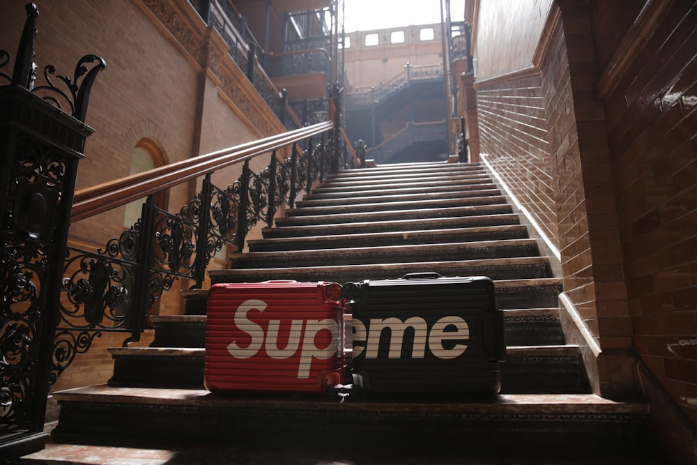 two black and red Supreme hard-case luggages