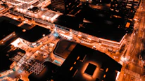 Aerial view of Brasília's iconic architecture illuminated at night with warm firelight tones.