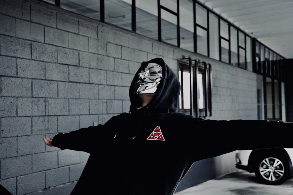 person wearing Guy Fawkes mask opening his arms