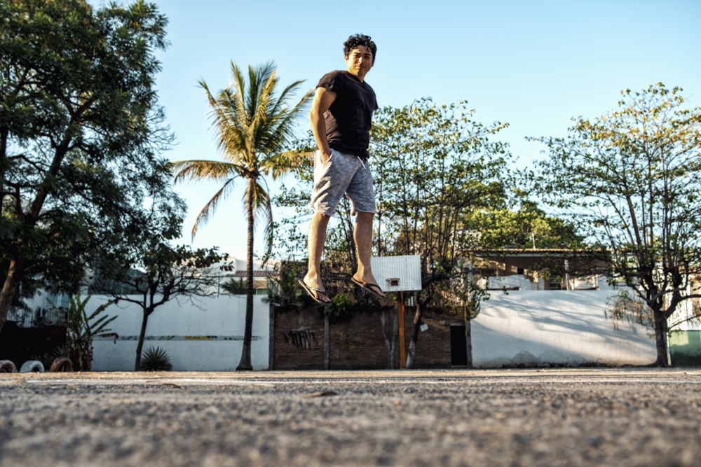 Photo en contre-plongée d’un homme debout sur un sol en béton à côté d’arbres