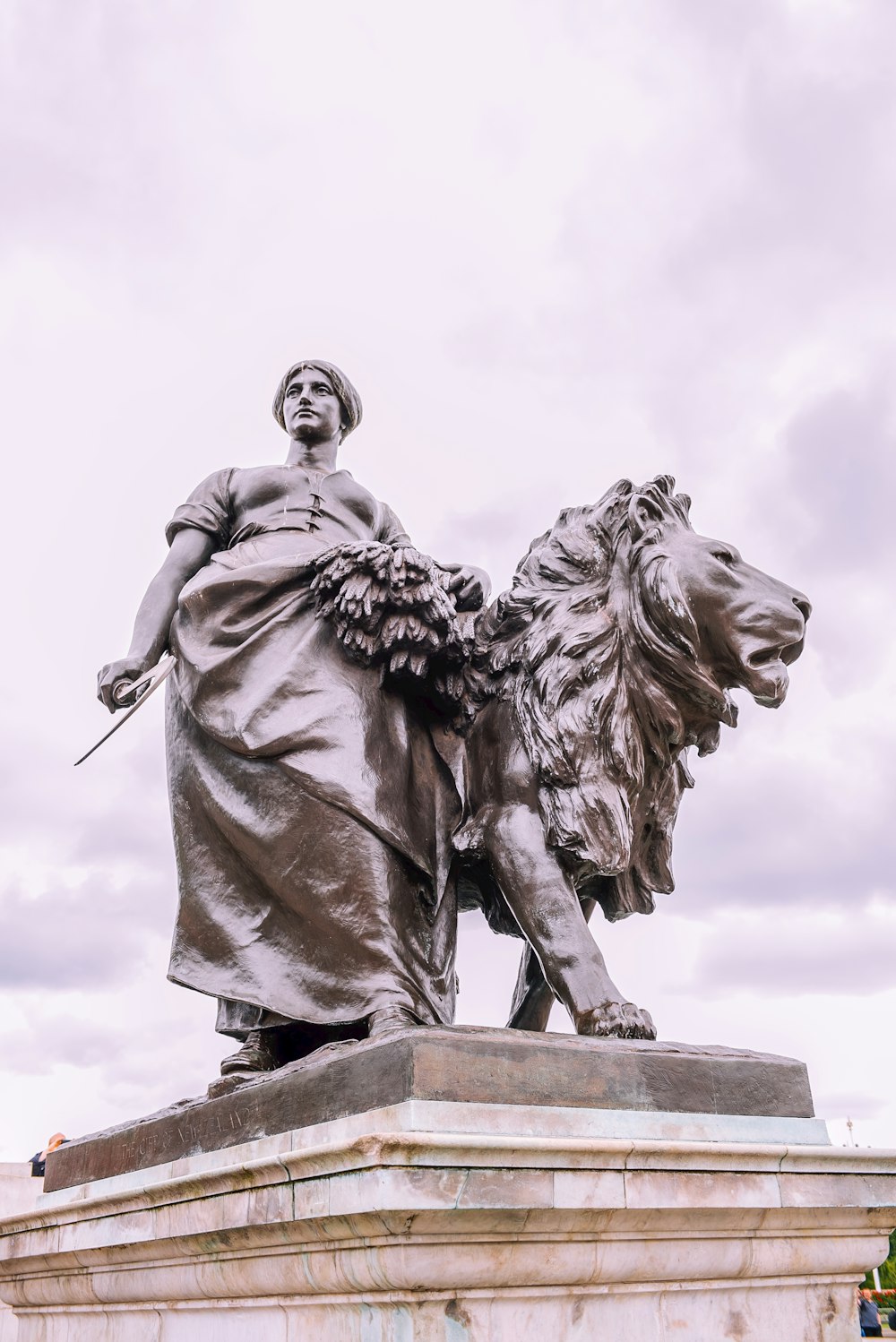 woman and lion statue on grey concrete pedestal