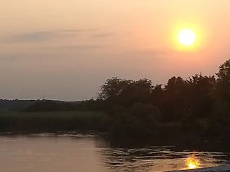 Sunset over the peaceful Tardoire river flowing through lush green valleys.