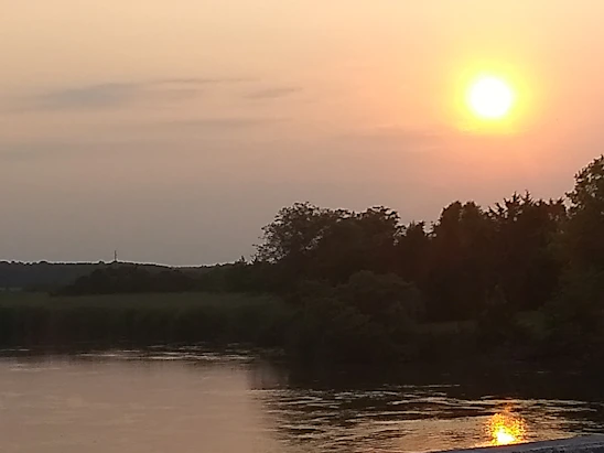 Sunset over the peaceful Tardoire river flowing through lush green valleys.