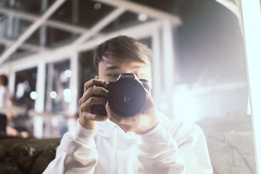 man wearing white dress shirt holding black DLSR camera