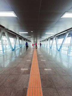 Tactile floor guiding path inside a modern shopping mall with people walking.