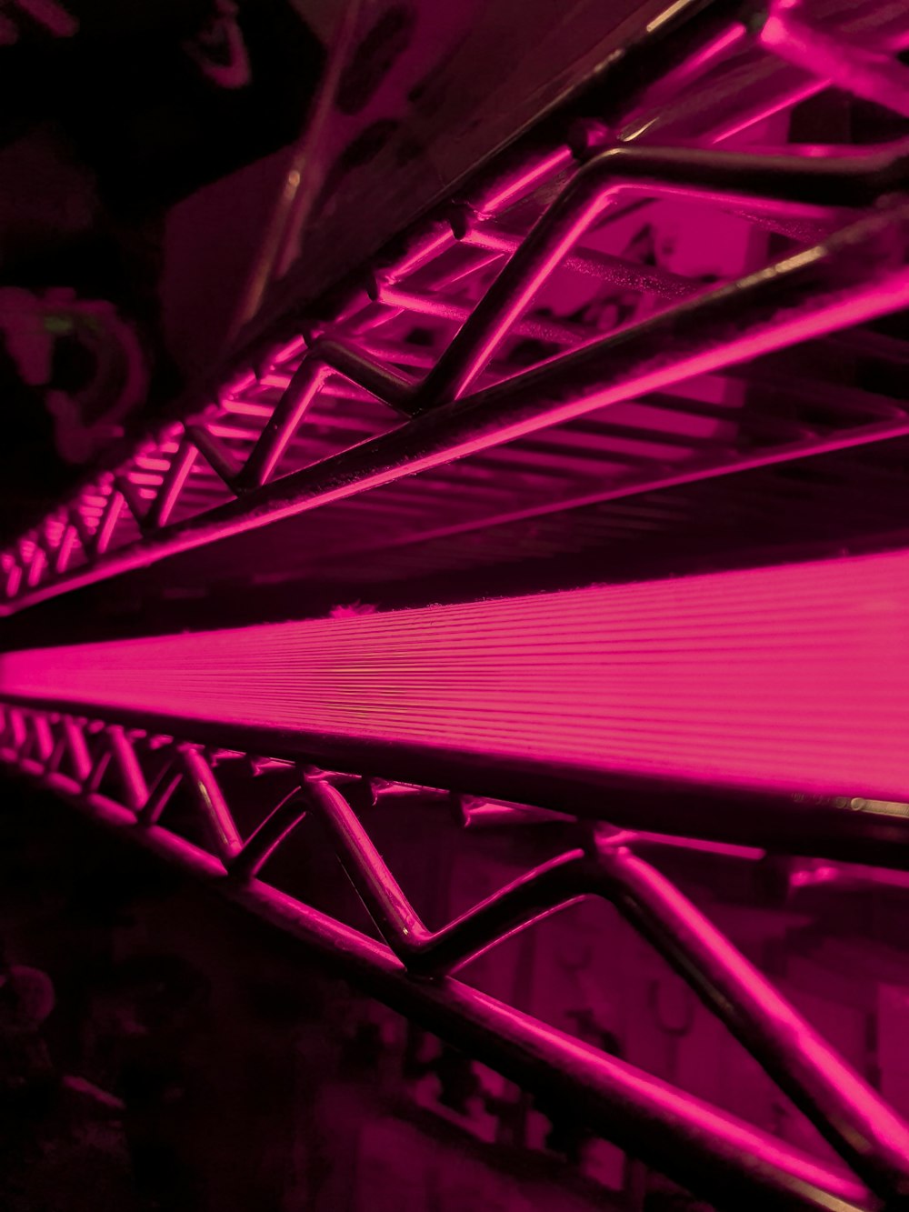 a close up of a metal structure with pink lights
