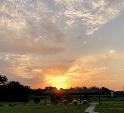 A vibrant sunset over the lush greenery of Parque Las Riberas Culiacán with families enjoying the park.