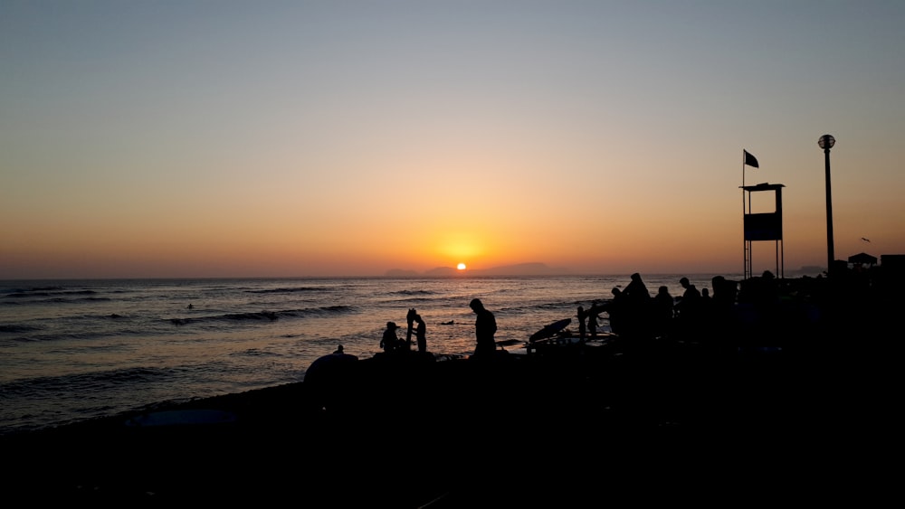 silhouette photo of three person standing near shoreline