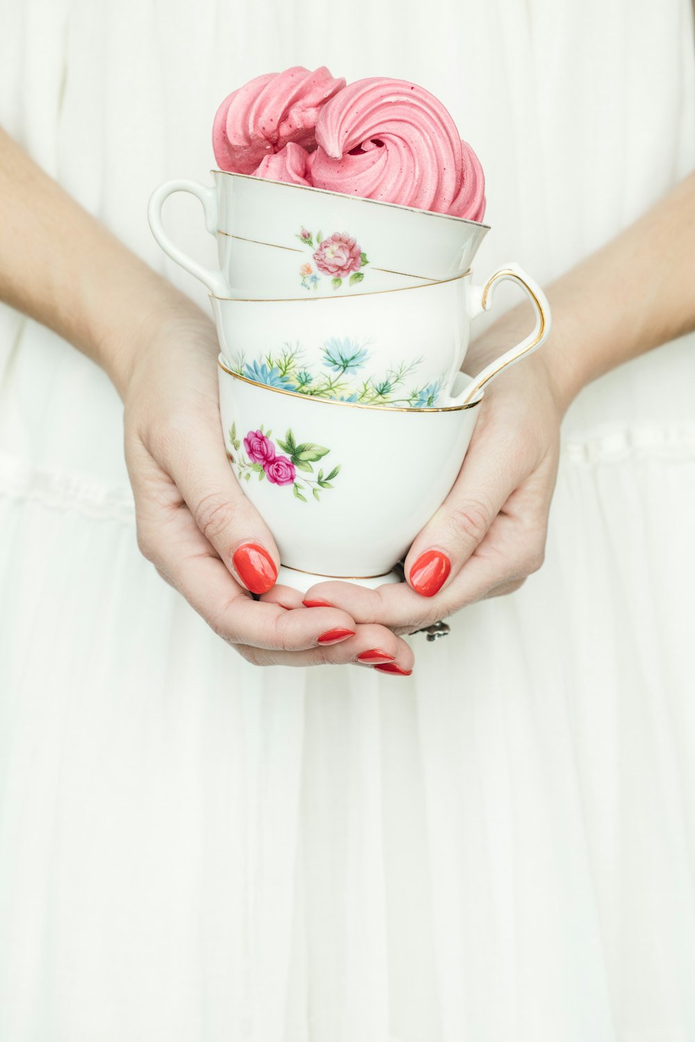 personne tenant trois tasses à thé en céramique florale