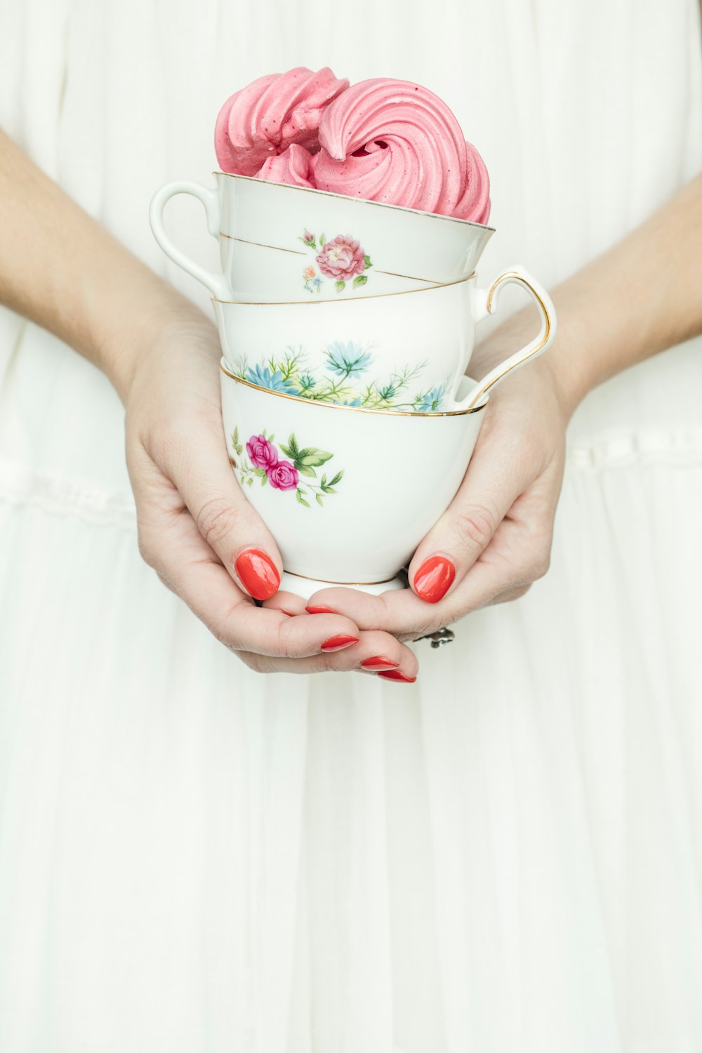 persona sosteniendo tres tazas de té de cerámica floral