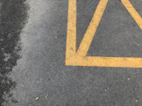 Close-up of freshly painted parking lines with vibrant yellow paint on smooth asphalt.