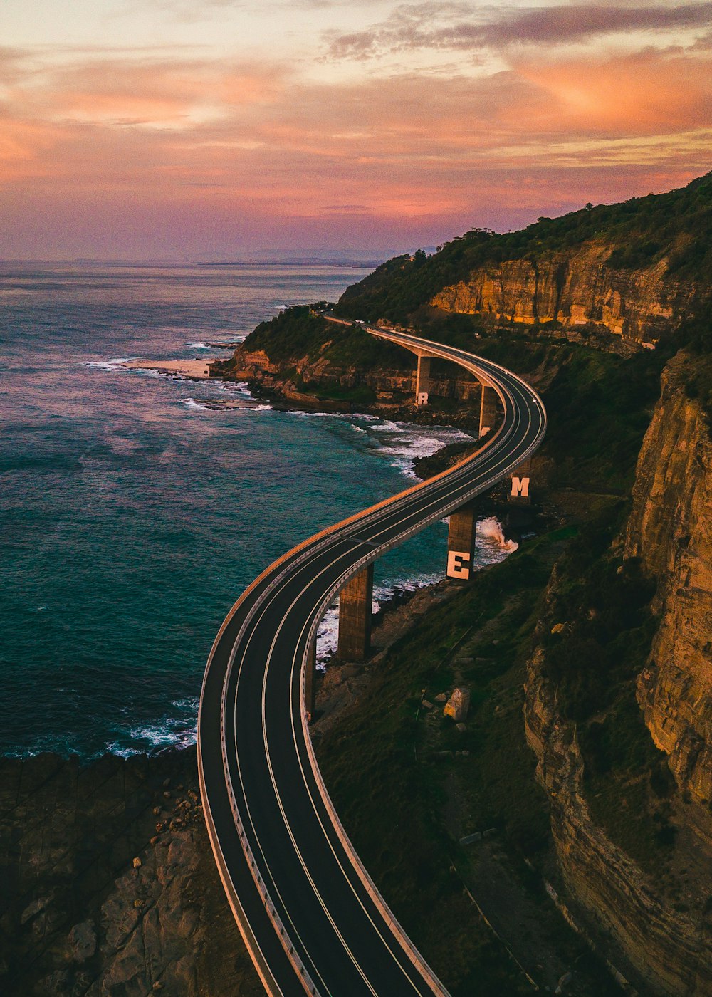 Photographie sélective d’une route vide près d’un plan d’eau pendant la journée