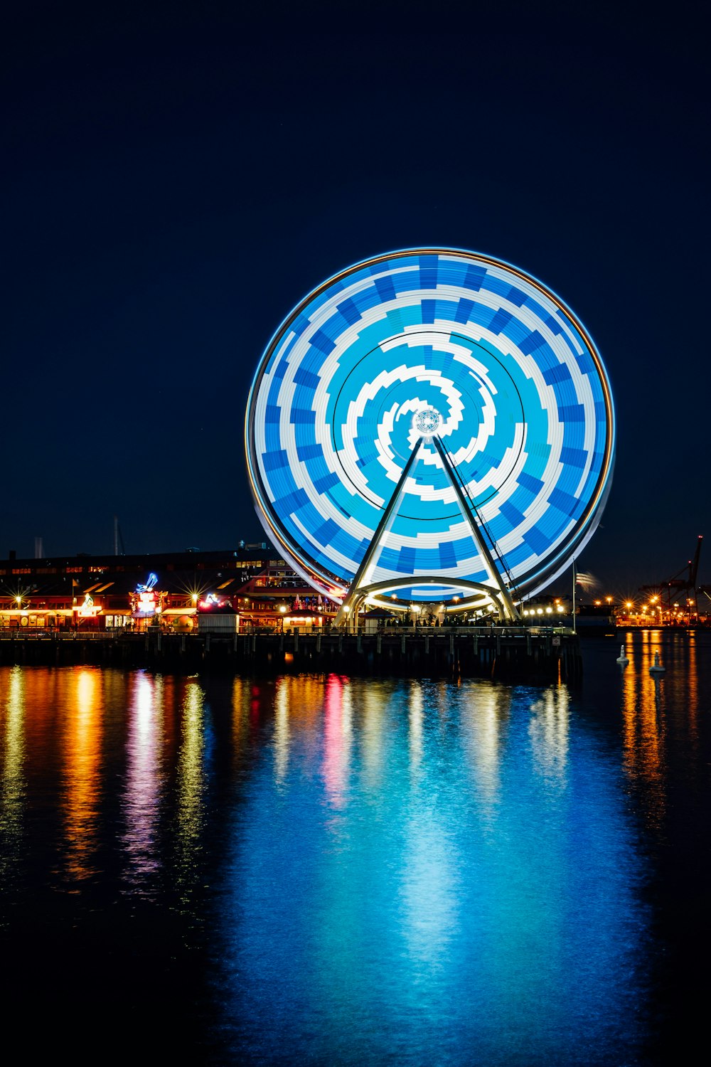 Grande roue avec lumière LED bleue se reflétant sur le plan d’eau pendant la nuit