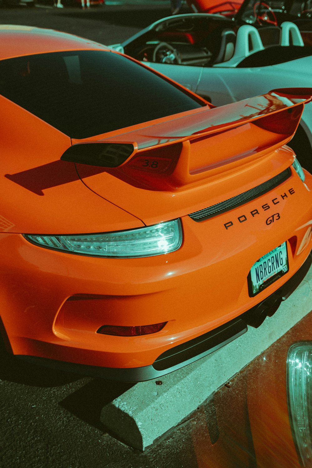 주황색 포르쉐 스포츠 쿠페는 흰색 컨버터블 자동차 근처에 주차되어 있습니다.