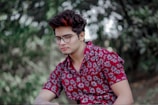 man wearing eyeglasses sitting near trees
