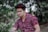 man wearing eyeglasses sitting near trees