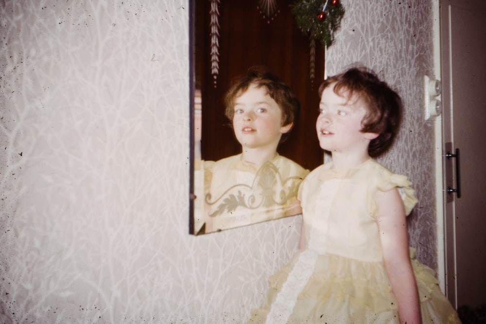 girl wearing beige dress standing in front of mirror