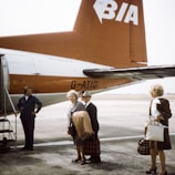 A group photo taken at an airport, with suitcases and boarding passes in hand, ready for takeoff.
