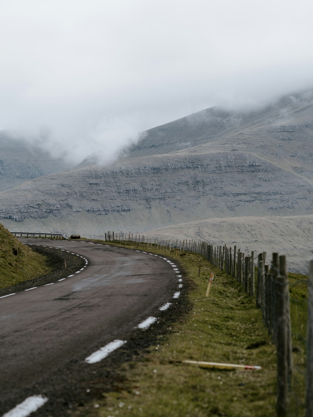 road near grey wooden fence near mountain