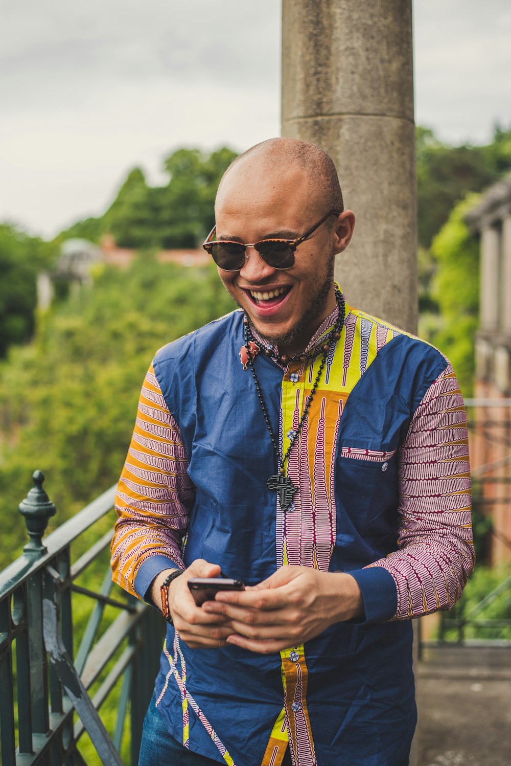 smiling man in multicolored dress shirt and brown sunglasses