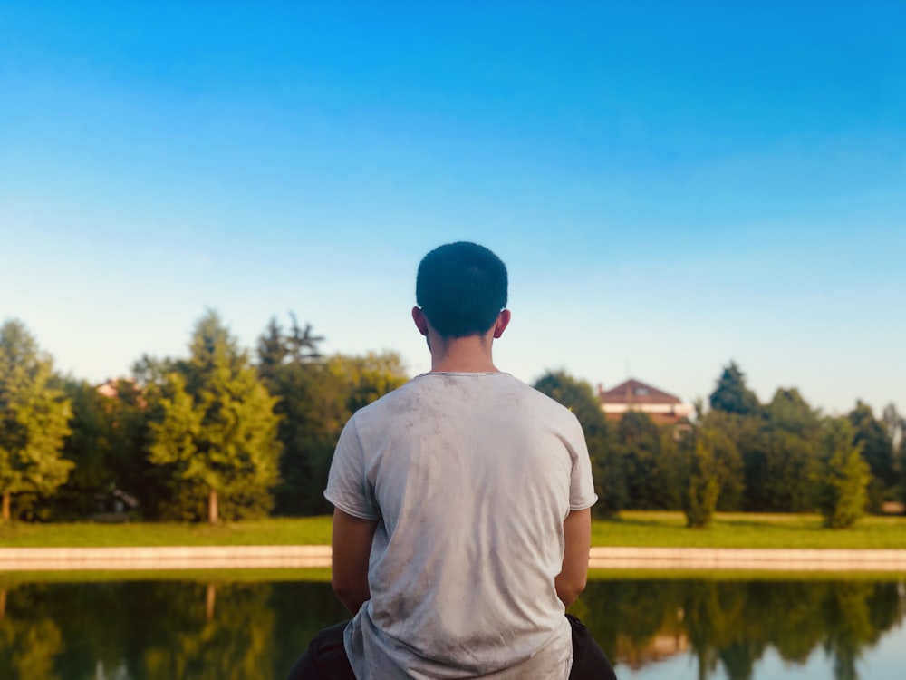 Hombre con camisa blanca sentado frente al estanque