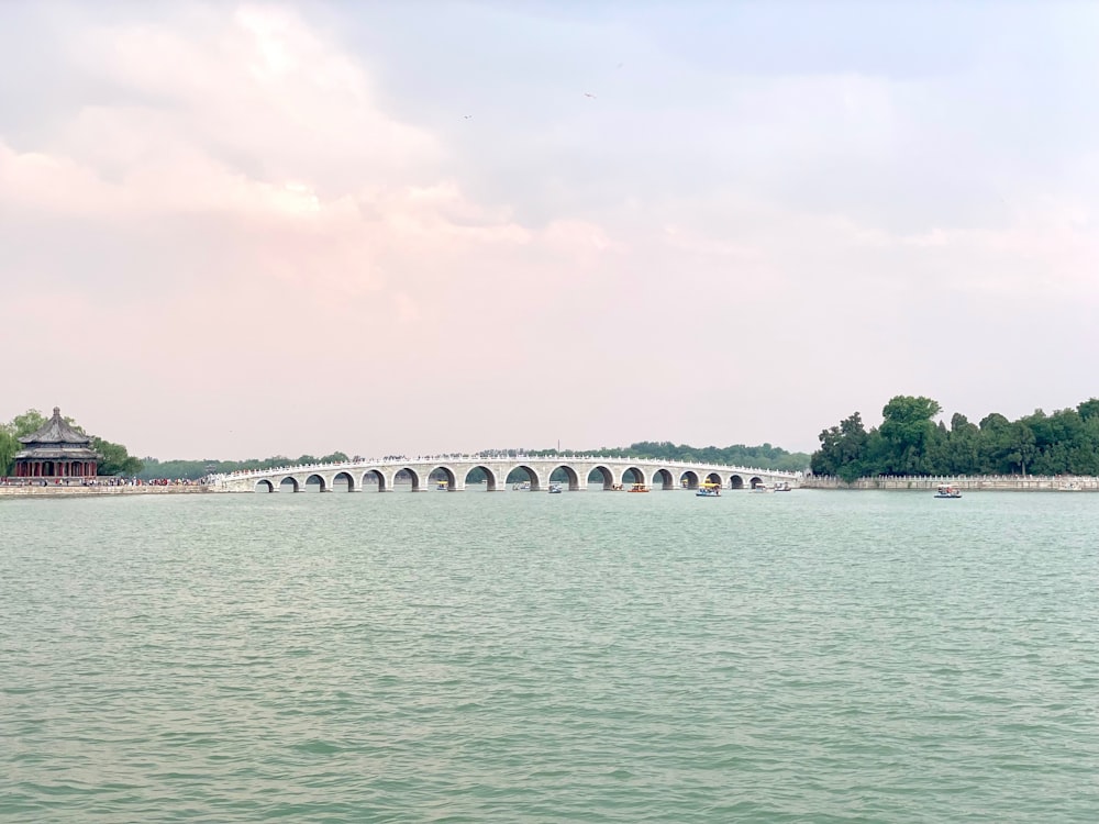 bridge with archs over body of water under gray sky