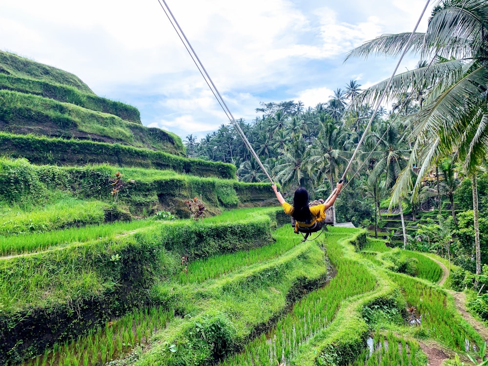 woman in yellow shirt doing swing beside green palm trees