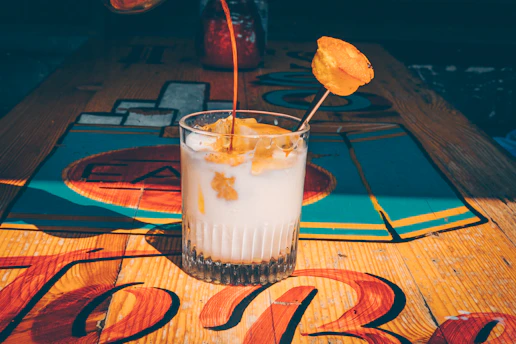 A glass filled with a creamy fruit juice blend topped with a swirl of ice cream.