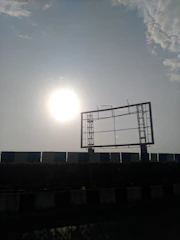 A striking red and black billboard being installed outdoors on a sunny day.
