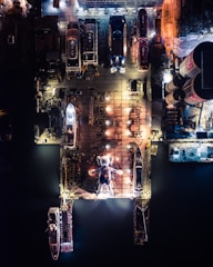 Night view of illuminated shipyard docks with ships moored.