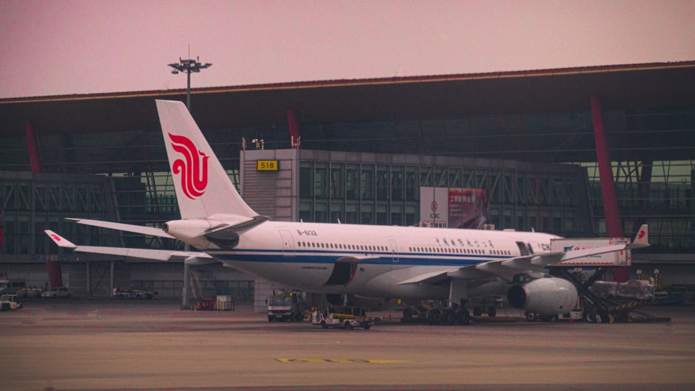 white and blue airplane beside building