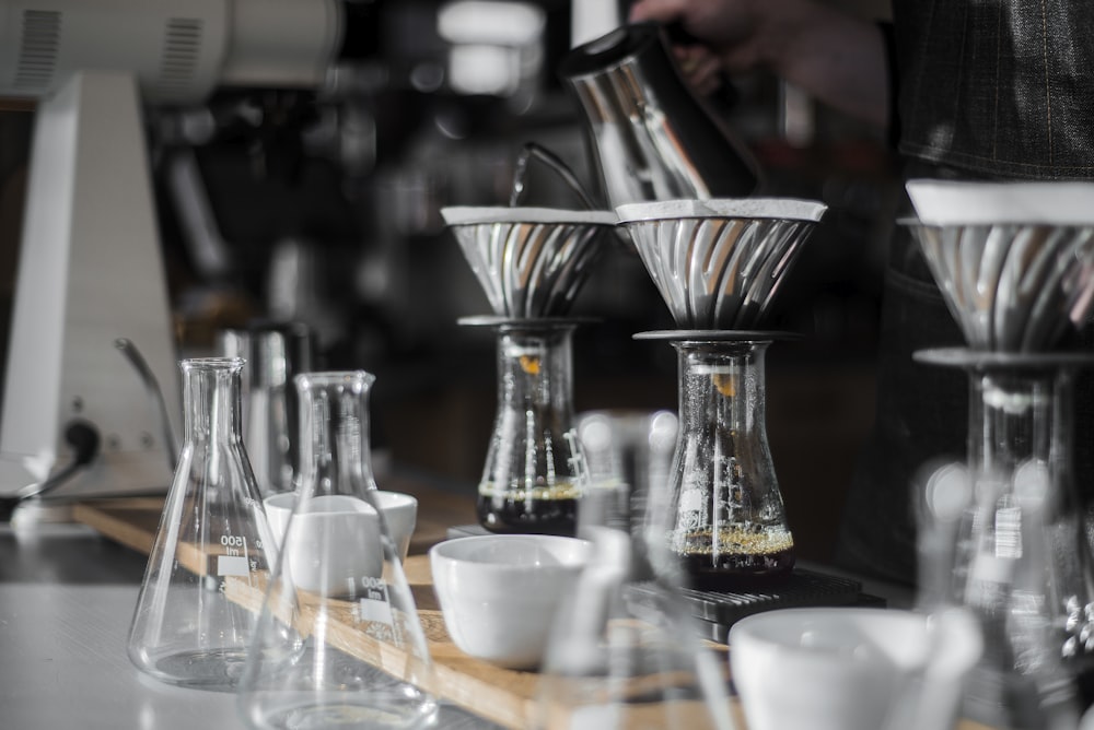 two clear glass beaker in front of white ceramic bowls