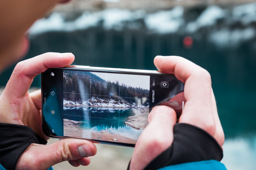 person taking photo of lake