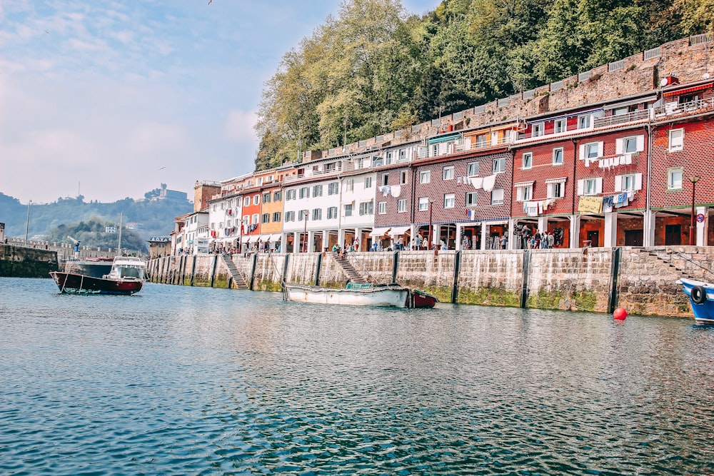 persone che camminano vicino a un edificio in cemento multicolore che visualizza il mare calmo sotto cieli bianchi e blu