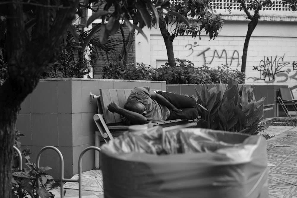 grayscale photo of man lying on bench