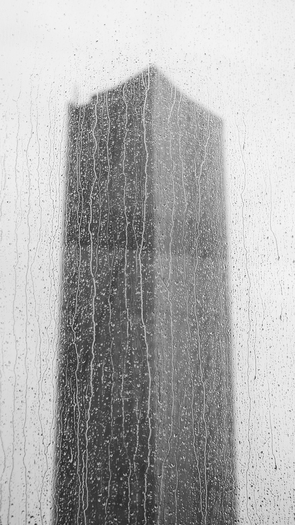 비에 젖은 창문을 통해 높은 건물이 보입니다