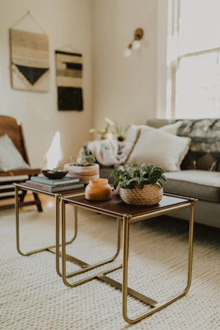 A cozy living room corner featuring a Nestoria bookcase filled with books and decorative items, complemented by textured wall art and woven nesting baskets.