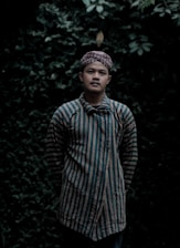 A serene portrait of an Amazonian shaman standing amidst lush green jungle foliage, holding traditional ceremonial tools.