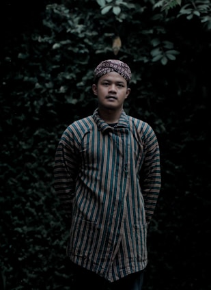 A serene portrait of an Amazonian shaman standing amidst lush green jungle foliage, holding traditional ceremonial tools.